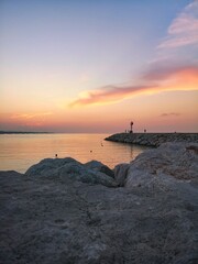 Vertical shot of a pink sunset over the coast of Senigallia, Italy - obrazy, fototapety, plakaty