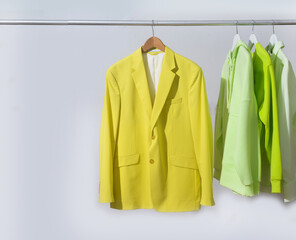 female, formal business light and dark green with yellow purple colour suit, jacket on hanger