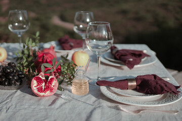 Table set with linen tablecloth and napkins for feast of Rosh Hashana, new Jewish year start , with traditional symbolic dishes and foods, pomegranate, Honey, Apple and wine. 