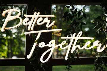 Fotobehang Wedding day neon text. Wedding venue decoration. Boho style leaves decorations. Rustic wedding party in wooden barn with glass windows. Closeup better together banner. © Paweł Michałowski