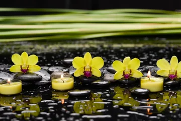 Foto op Aluminium Still life of with  Yellow orchid ,candle and zen black stones on wet background,  © Mee Ting