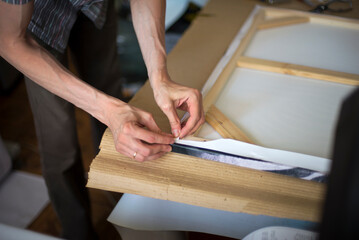 close up of a person hands stretching the canvas on the stretcher