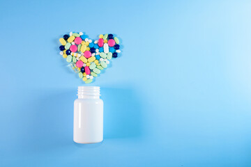 Assorted pharmaceutical medicine pills, tablets and capsules for the treatment of heart disease. Heart shape and bottle of pills. Copy space for text