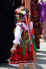 Small girl in traditional folk costume from Krakow region, Poland, while joing public holiday in the street