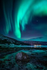 Vertikale Aufnahme von Polarlicht Aurora Polaris am Himmel mit der Reflexion auf der Wasseroberfläche