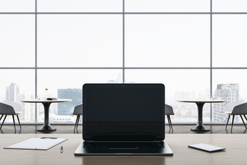 Close up of empty laptop screen on wooden office desktop with supplies on panoramic window and city view backdrop. Mock up, 3D Rendering.