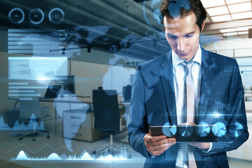 businessman using tablet with abstract map and business chart hologram on blurry office interior background. Investor, finance and financial dashboard concept. Double exposure.