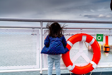Little girl on a sailing ship looking away towards the storming clouds.  Close up of a girl next to...