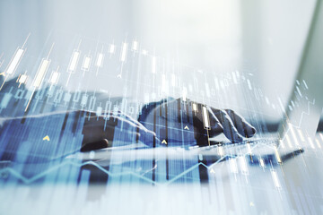 Multi exposure of abstract financial graph with hand typing on laptop on background, financial and trading concept