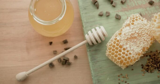 Honey background. Sweet honey in a glass jar, honeycombs, propolis and pollen on the table.