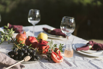 Table set with linen tablecloth and napkins for feast of Rosh Hashana, new Jewish year start , with traditional symbolic dishes and foods, pomegranate, Honey, Apple and wine. 