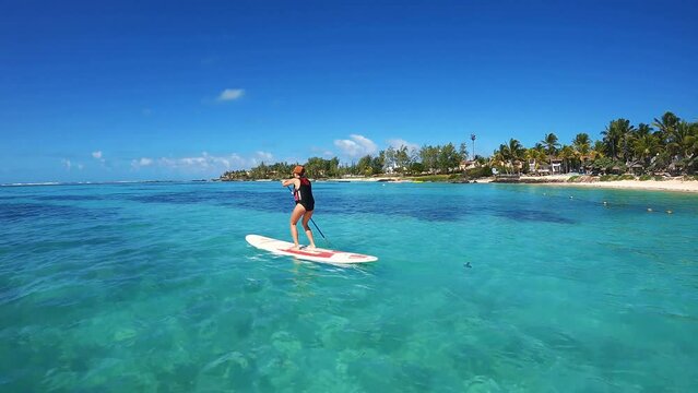 Woman paddling on a stand up paddle board in front of the coast of Mauritius