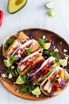 Top View Of Crispy Fish Tacos Tortillas With Avocadoes And Chilies On A Wooden Platter.