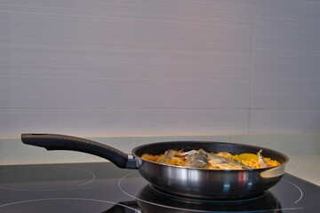 Cooking process of a fish dish in a cooking pan placed on a stove