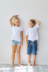 Cool kids, little boy and girl measure their height a