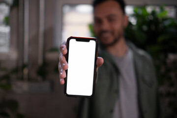 Businessman showing smart phone with blank screen in office