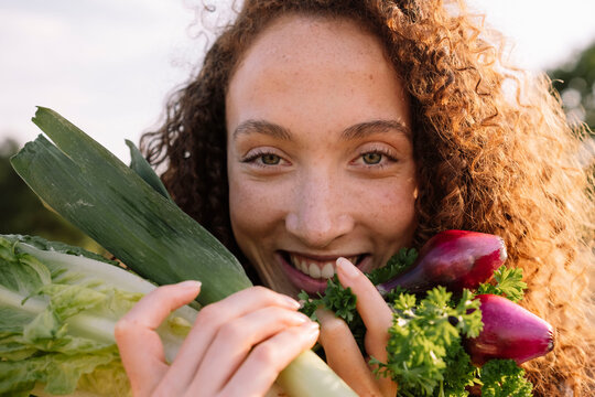 Smiling woman holding fresh organic vegetables