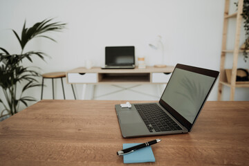 Laptop by adhesive note and pen on table in office