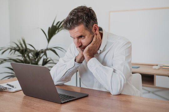 Tired businessman staring at laptop in office