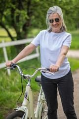 Fototapeta premium A woman in sportswear with a bike in the park feeling cheerful