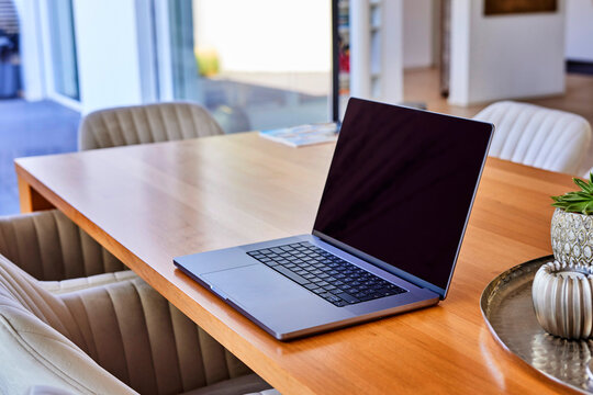 Laptop on wooden dining table at home