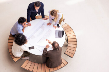 Multiracial business colleagues discussing over document on table in corridor