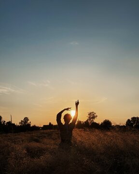 Silhouette of a woman dancing in a field at sunset, Belarus