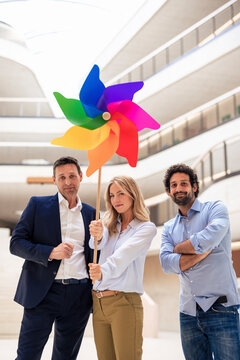 Businesswoman holding pinwheel toy amidst colleagues in lobby