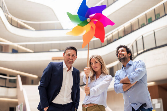 Businesswoman holding pinwheel toy by colleagues in lobby