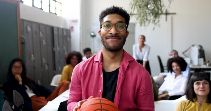 Portrait of smiling businessman holding basket ball in office