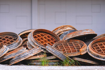 Pile of many old rusty manhole covers on the ground for recycling