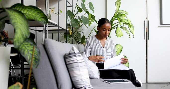 Young businesswoman sitting on couch looking through papers