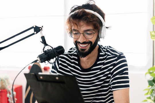 Happy man reading script and recording through microphone at home studio