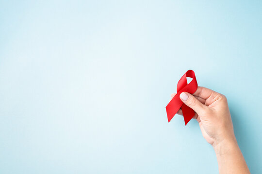 World AIDS Day card with hand holding red ribbon.