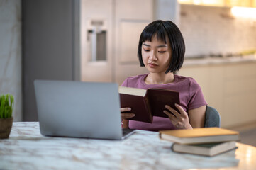 Pretty young asian girl reading a book and looking involved