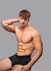 Advertising banner with young handsome caucasian athletic man on gray background. Portrait of man with beautiful athletic body who is dressed boxers and posing near copy space.