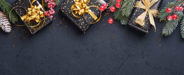 Merry Cristmas. Holiday gift box or present with ribbon, golden confetti and gold baubles on black...
