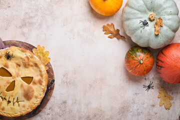 Halloween food. Homemade pumpkin pie or tart with a scary face for Halloween on a wooden table. Copy space. Halloween food concept.