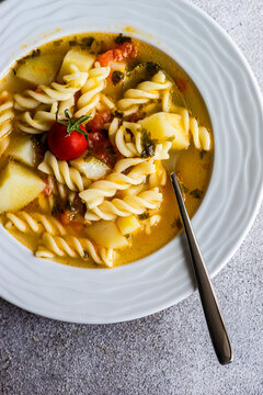 Overhead view of a bowl of homemade pasta, potato, tomato and vegetable soup