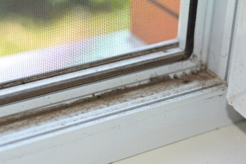  A view from inside the house of a dusty window. A dirty uPVC window frame that needs to get cleaned.