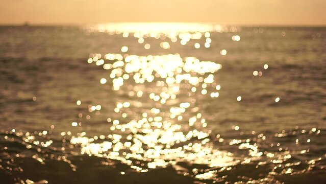 Abstract nature summer ocean sunset sea background. Small waves on water surface in motion blur with bokeh lights from sunrise. Holiday, vacation and recreational background concept. Slow motion