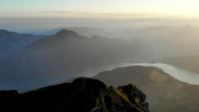 Aerial flight around the summit of Niederbauen Chulm on a golden summer morning in the Swiss Alps with a view of Mythen, Rigi, Burgenstock, Pilatus and cliffs above Lake Lucerne