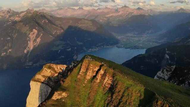 Aerial flyover towards the summit of Niederbauen Chulm with a view of Uri and Lake Lucerne fjords on a summer evening in the Swiss Alps
