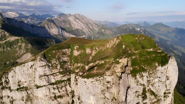 Aerial view of Niederbauen Chulm on a golden summer morning in the Swiss Alps with a spinning view from the peak's cliffs towards the fjords of Lake Lucerne, Uri, Mythen and the rising sun