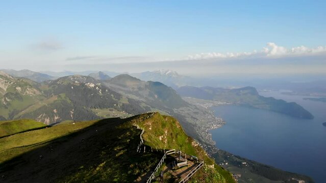 Aerial flyover over Niederbauen Chulm in Uri, Switzerland overlooking Lake Lucerne with a view of Pilatus, Burgenstock and the summit's cliffs with a hiker at the viewpoint