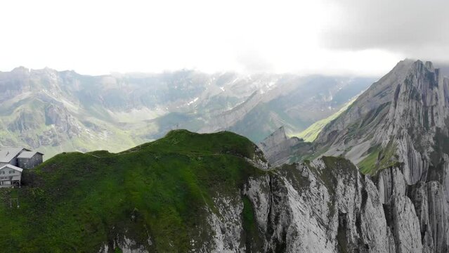 Aerial flyover alongside  Schafler ridge in Appenzell, Switzerland with from the Schafler hut towards Alpenturm with cliffs, mountain peaks and lush summer green mountainside in view