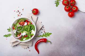 Healthy vegetarian salad with fresh arugula, cherry tomatoes, soft cheese and cucumbers