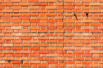 Cracked damaged orange brick wall facade as background and texture