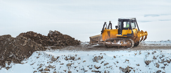 Bulldozer working on road construction site in grading phase in winter time