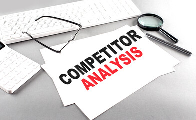 COMPETITOR ANALYSIS text on a paper with keyboard, calculator on grey background